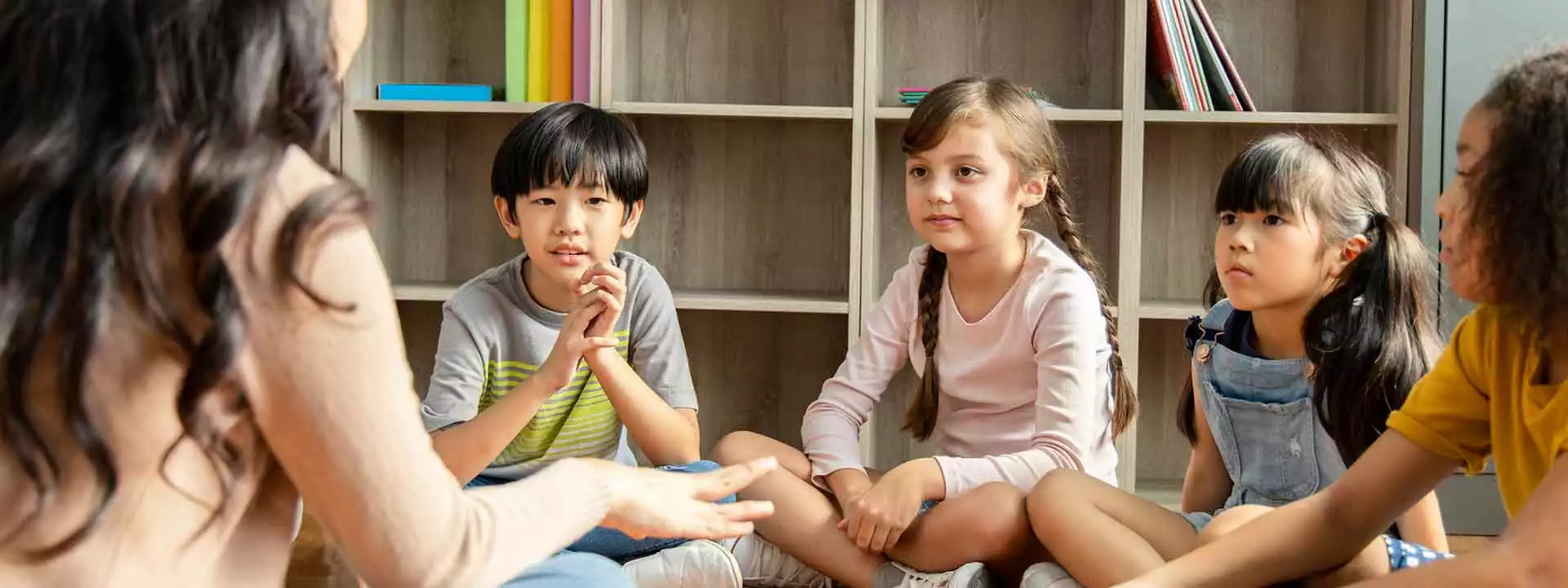 A group of children sitting around a teacher.