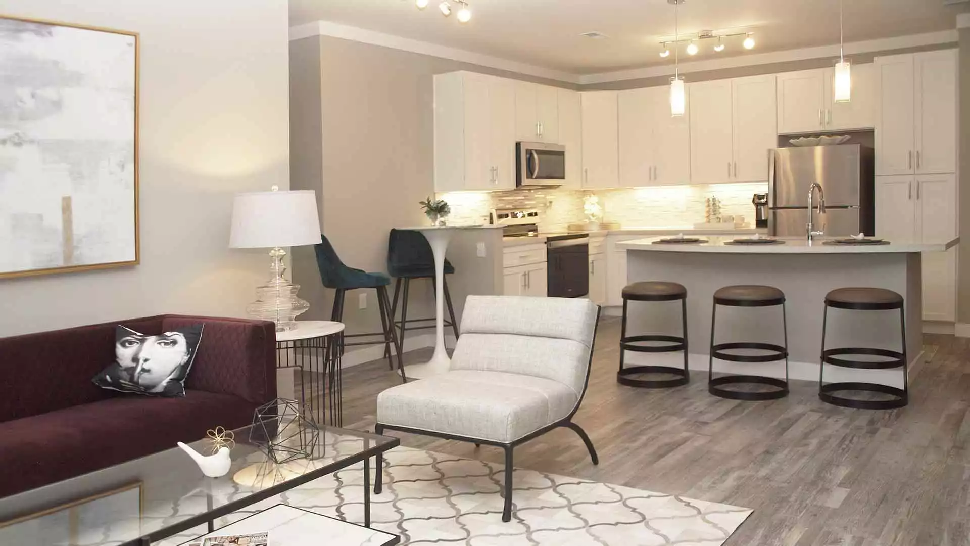 A modern living room with wood-grain flooring that leads into an open kitchen.