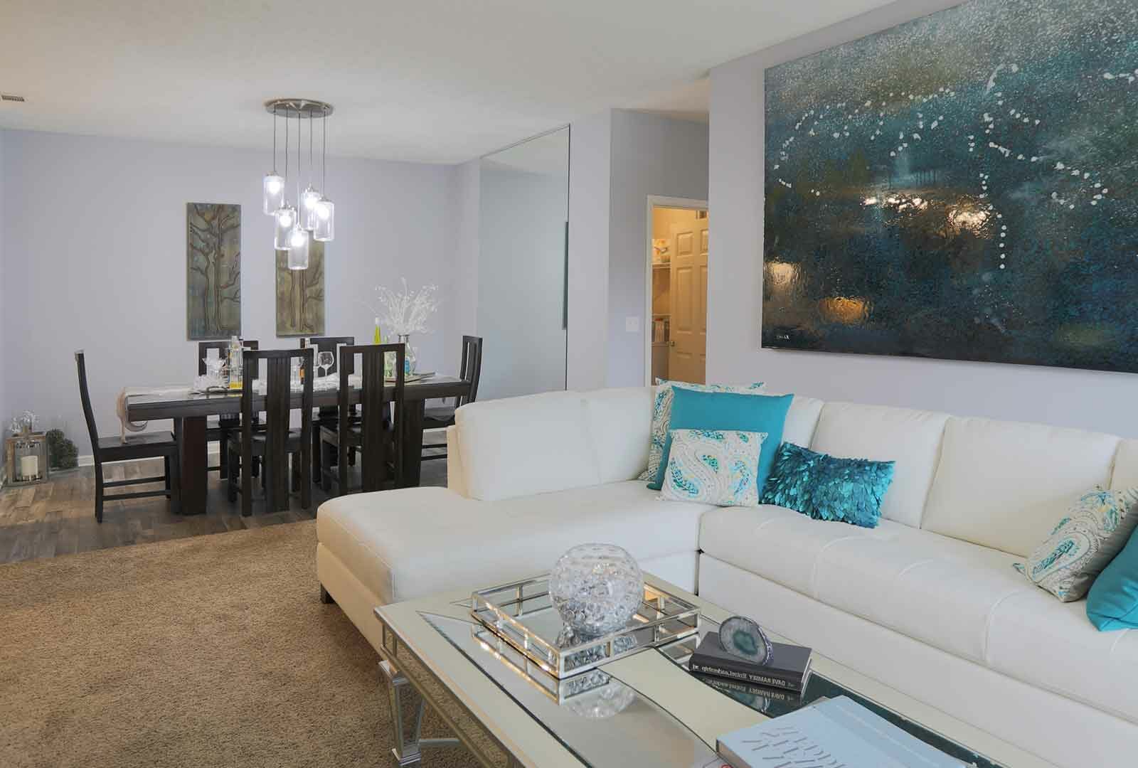 A large, carpeted living room and open dining room with wood-grained flooring.