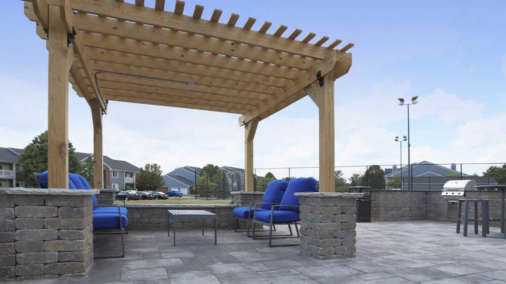 Outdoor stone terrace with lounge chairs and gas grill.