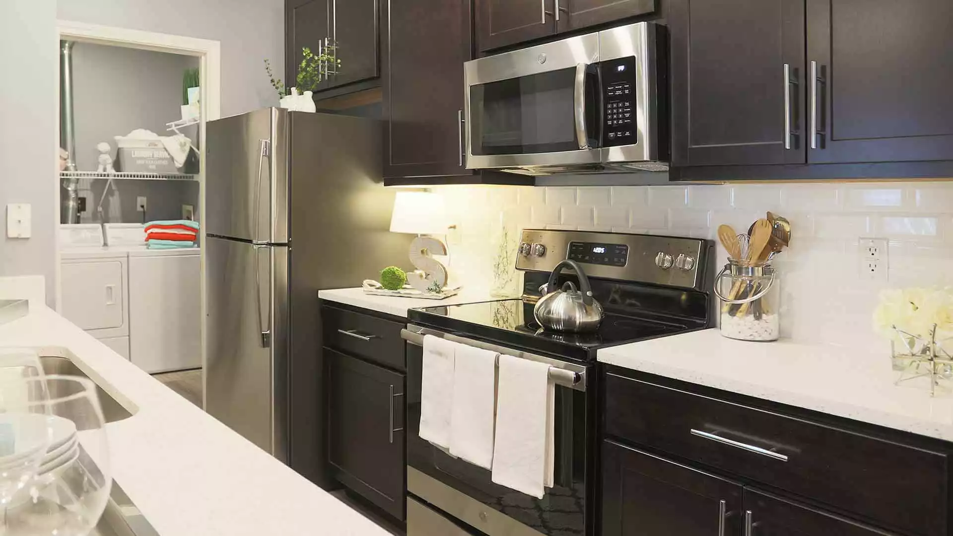 Apartment kitchen with stainless steel appliances and dark wood cabinets.