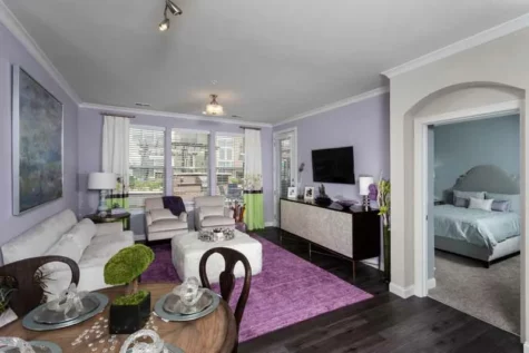 Decorated living room with hard woodgrain flooring connected to a bedroom.