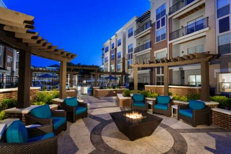 Beautiful apartment terrace with fire pit surrounded by lounge chairs.