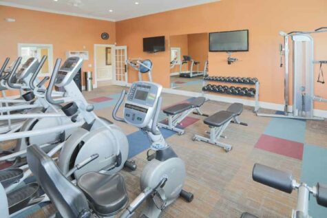 Fitness room equipped with machines and barbells.