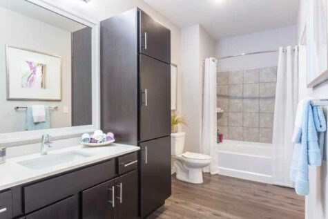 A large bathroom with a combination shower and tub, vanity, and cabinet storage.