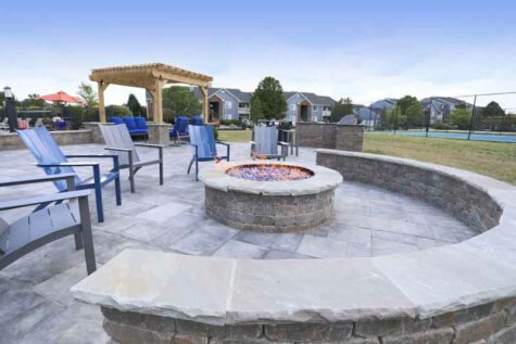 Patio chairs surrounding a stone gas fire pit.