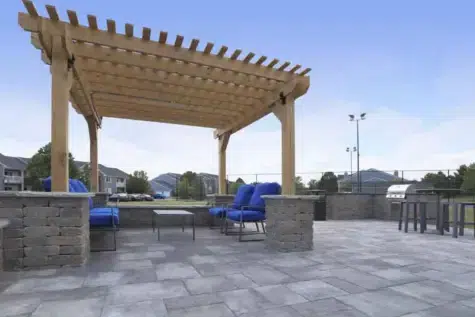 Outdoor stone terrace with lounge chairs and gas grill.
