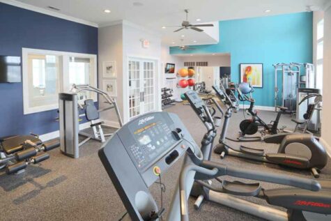 Open fitness room with treadmills, gym equipment, and free weights.