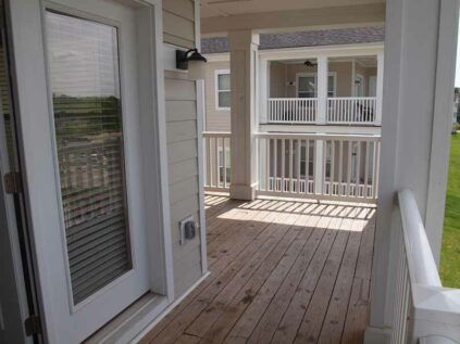 Covered balcony with wood flooring.