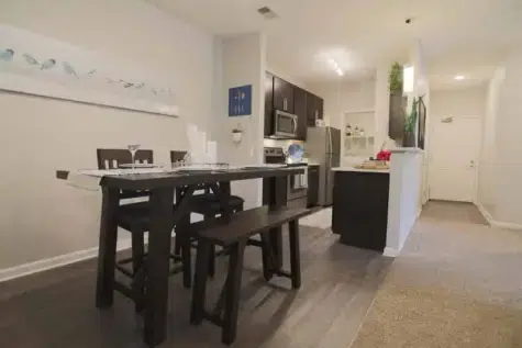 Dining room and kitchen with dark wood cabinets and table.