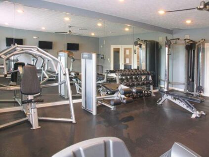 Fitness center filled with gym equipment and large mirrors.