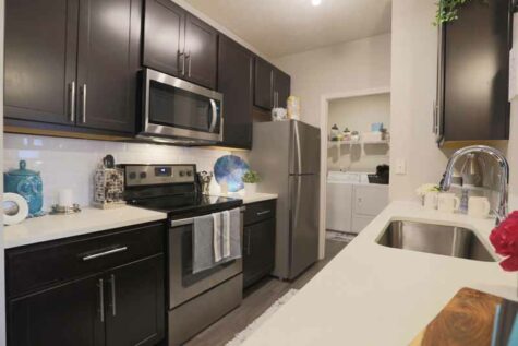 Beautiful kitchen with dark accessories with laundry room connected.