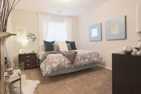 Beautiful bedroom with carpet and large window with blinds.