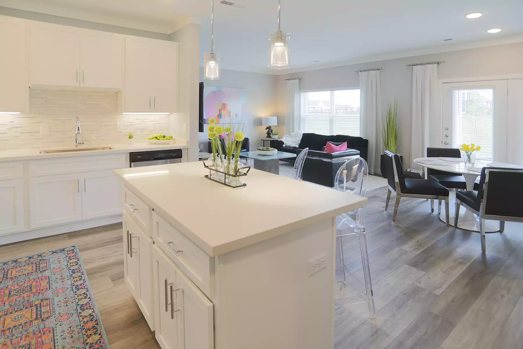An open concept living space featuring a dining room, living room, and kitchen with white cabinets.