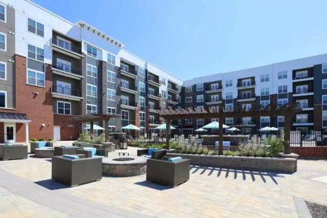 An outdoor firepit and lounge area immediately outside of a large apartment building.