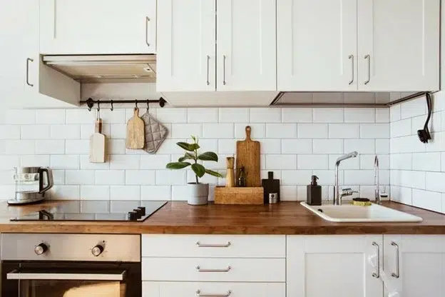 A clean kitchen with white cabinets and wood accents.