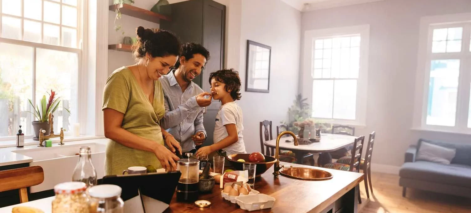 Family of three having fun and preparing breakfast together in the kitchen.