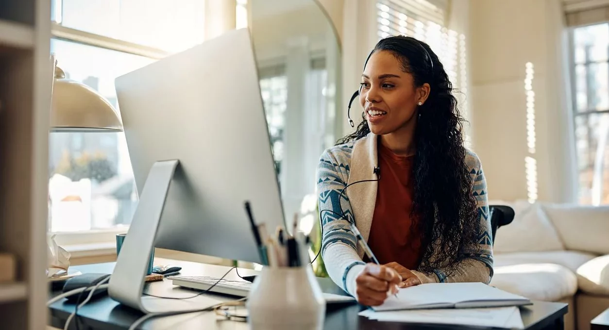 Worker discusses business objectives with colleagues over a video call while working from home at a desk