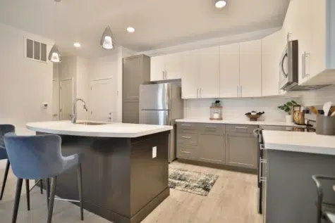 Barstool area for eating with quartz countertops, sink. L-shape kitchen with quartz countertops, stainless steel appliances. Wood floors at Clocktower West Chester, Ohio Apartments