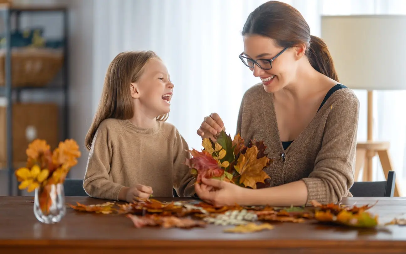 A happy mother and daughter organize fall leaves for DIY crafts.