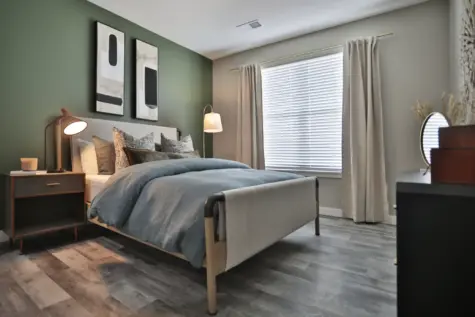 Master bedroom with wooden plank floors, green walls, large window and spacious area at Altair Apartments in Florence, KY