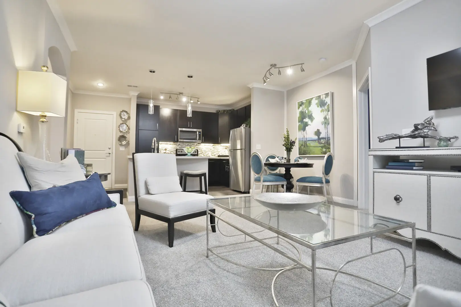Living room view of a two-bedroom home at 49Hundred Apartments featuring large windows, modern finishes, and an open layout that flows seamlessly into the kitchen and dining areas.