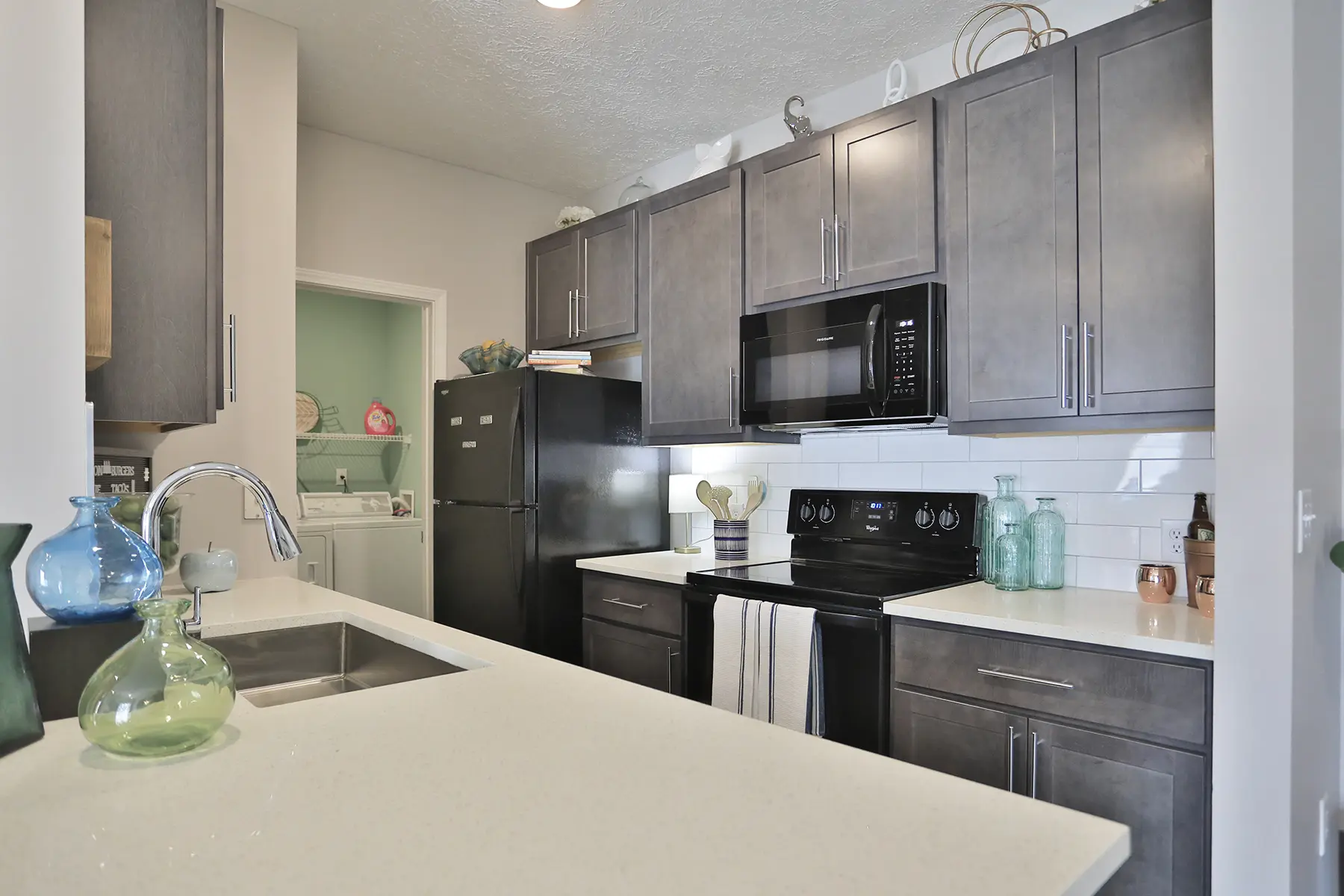 Kitchen at Emerald Lakes Apartments featuring quartz countertops, black appliances, solid wood cabinets, and chrome finishes, offering a modern and functional cooking space.