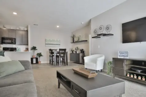 Full model view at Emerald Lakes Apartments from the dining room, showcasing an open-concept layout with sightlines into the living room, kitchen with modern finishes, and guest wing of the home.