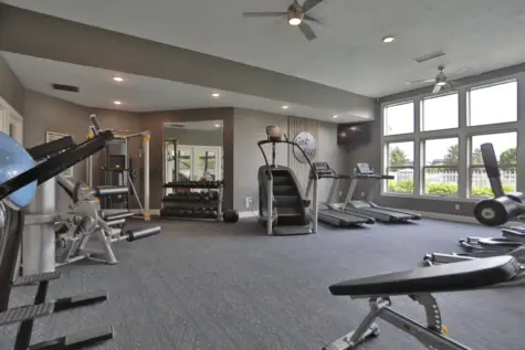 Fitness center at Wellington Place Apartments showing a StairMaster and multifunctional weight machine, set in a modern space designed for strength and cardio training.