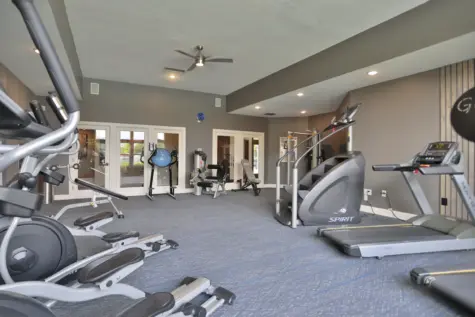 Fitness center at Wellington Place Apartments featuring cardio machines including ellipticals and treadmills, offering a well-equipped space for residents to stay active.
