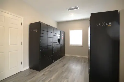 Luxer Package System at Wellington Place Apartments with secure lockers and a digital access screen, providing residents with convenient 24/7 package pickup and real-time delivery notifications.
