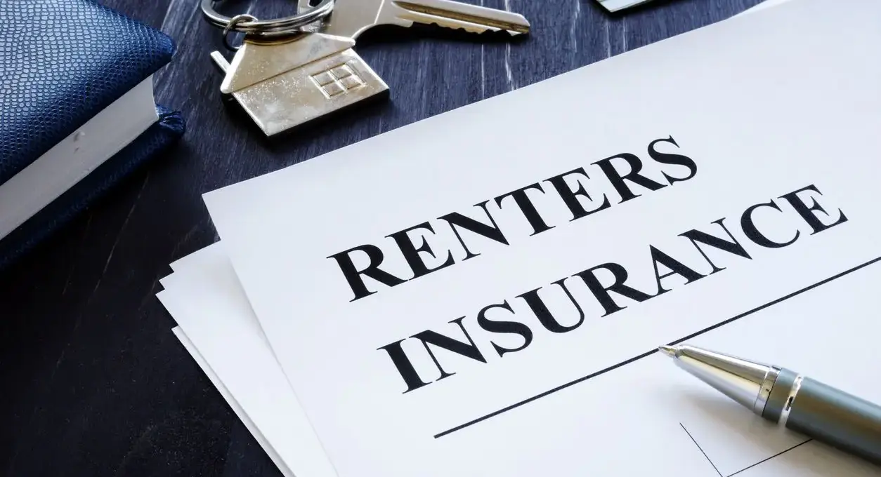 A renters insurance policy agreement sitting next to keys for an apartment.