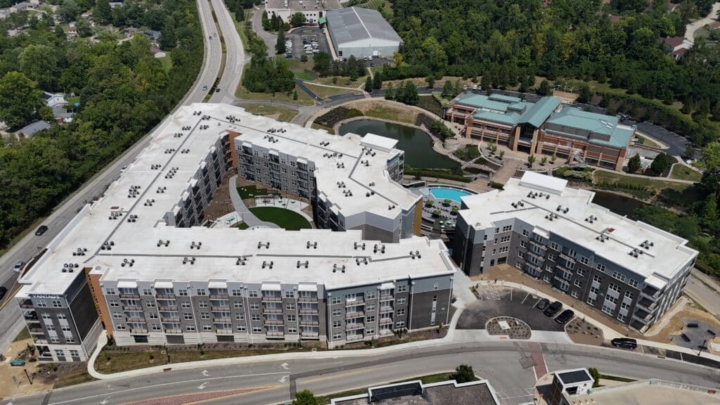 Aerial view of Vantage apartments with pool, green courtyard, pond, highway, and surrounding Cincinnati area.