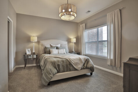 Primary bedroom at Kendal on Taylorsville showcasing plush carpeting, large windows for natural light, and a comfortable modern design.