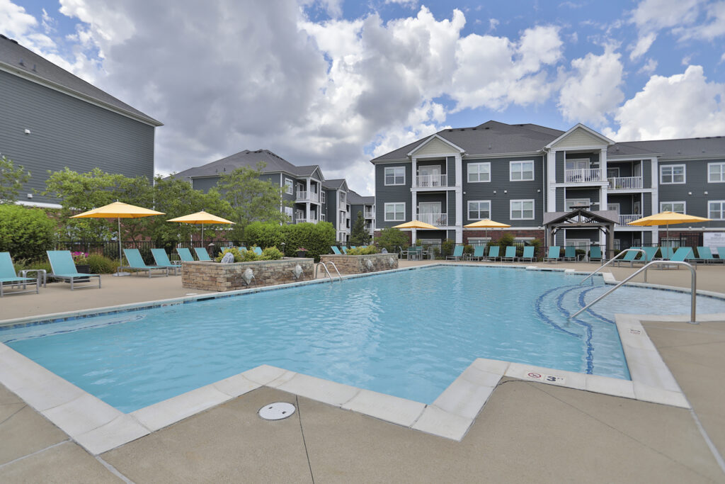 Resort-style swimming pool at Kendal on Taylorsville featuring in-pool lounge seating, shaded cabanas, and a relaxing atmosphere for residents to unwind.