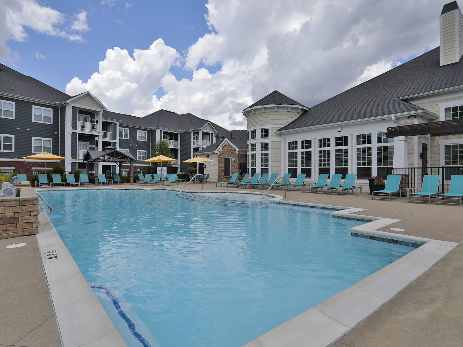 Resort-style swimming pool at Kendal on Taylorsville featuring in-pool lounge seating, shaded cabanas, and a relaxing atmosphere for residents to unwind.
