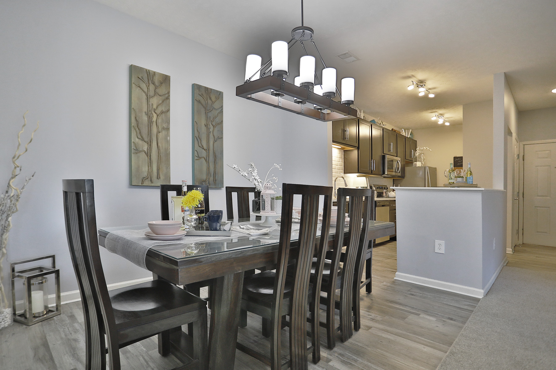 Modern kitchen with white cabinetry, stainless steel appliances, and a dining area with stylish seating.