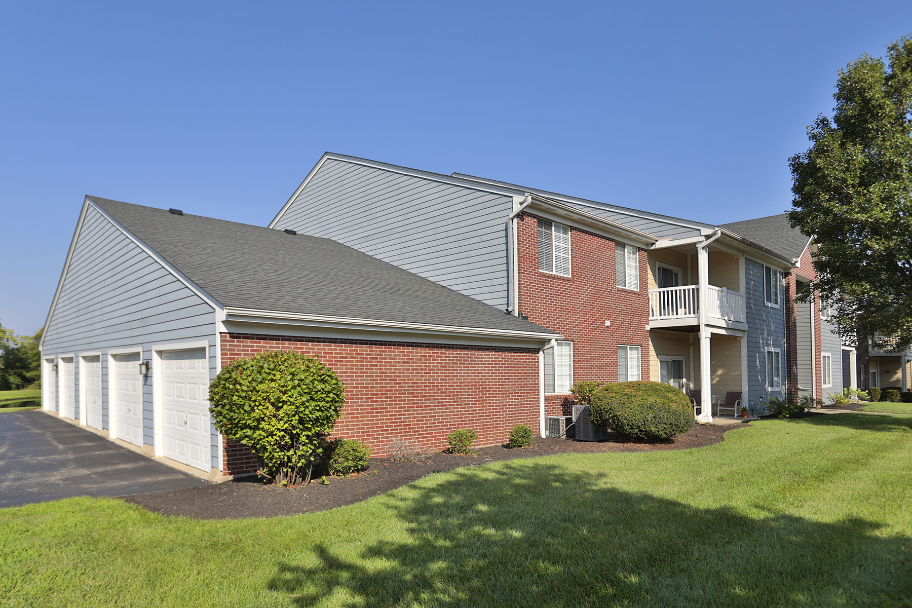 Street-level view of apartment homes with attached garages and upper-level balconies.