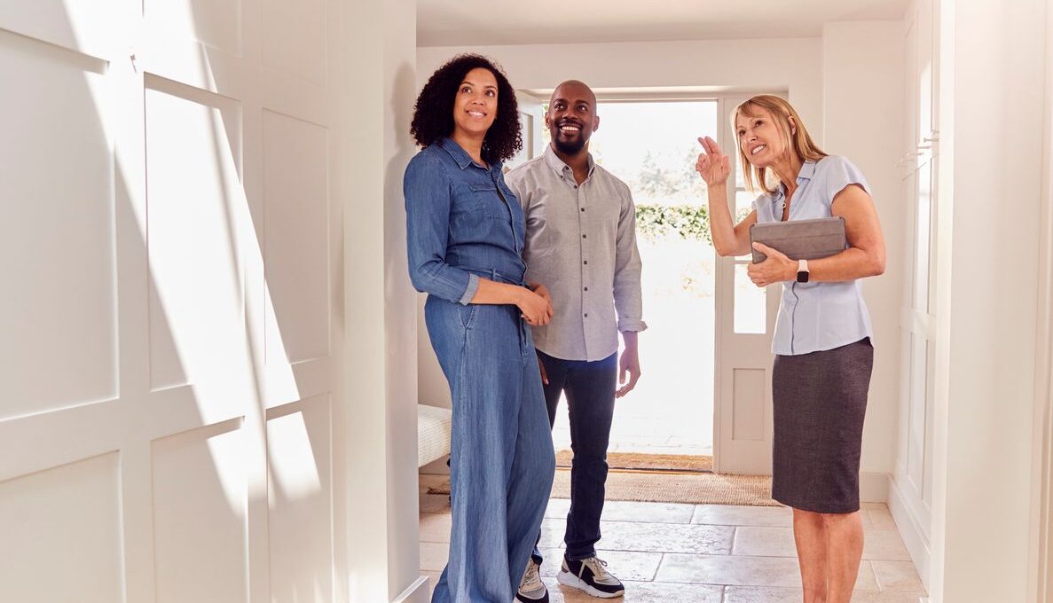 A happy couple smiles as they tour an apartment with a leasing agent.