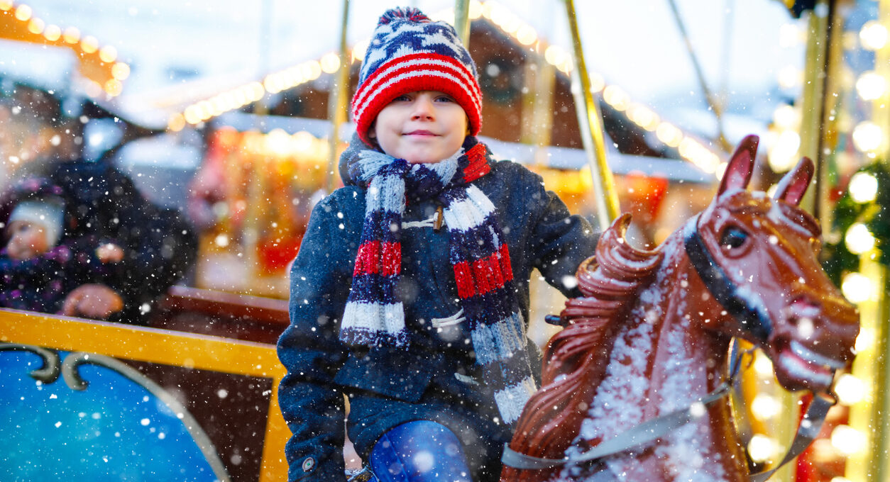 A child riding on a carousel in winter apparel