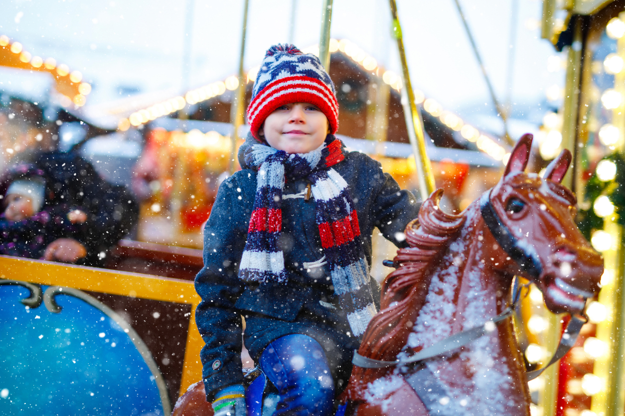 A child riding on a carousel in winter apparel