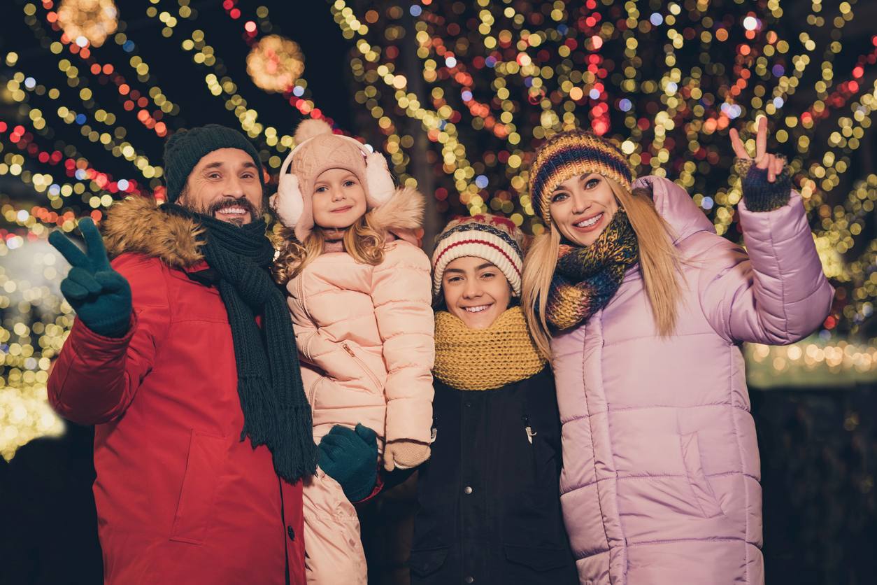 A family smiles and stands underneath a dazzling Louisville Christmas lights display.