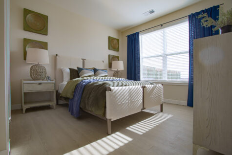 Spacious secondary bedroom at Relay 129 featuring large windows, neutral finishes, and access to a walk-in closet.