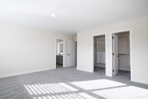 Spacious primary bedroom in two-story townhome at Relay 129 with large windows and two walk-in closets.