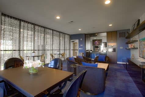 Resident café and lounge at Allure Apartments featuring plush seating, dining tables, coffee station, and decorative shelving.