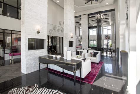 Luxury resident lounge at Allure Apartments with white stone fireplace columns, modern seating, and dramatic two-story ceilings.