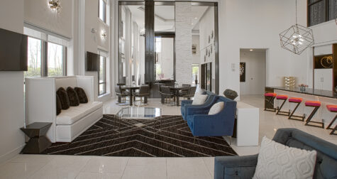 Contemporary clubhouse seating area at Allure Apartments with blue velvet chairs, glass coffee tables, and open-concept gathering spaces.