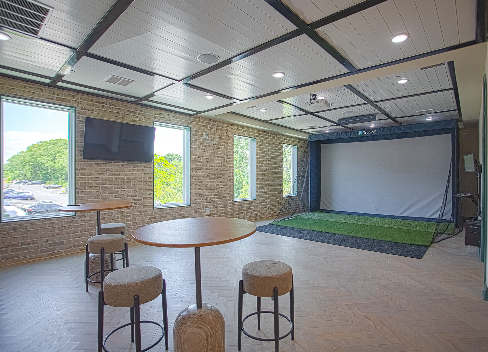 Resident entertainment lounge with TruGolf simulator, café-style seating, and modern finishes at Relay 129 by HILLS Properties in Liberty Township, Ohio.