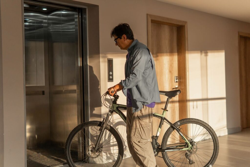 A man walks his bicycle onto the elevator in the hallway near his third-floor apartment.