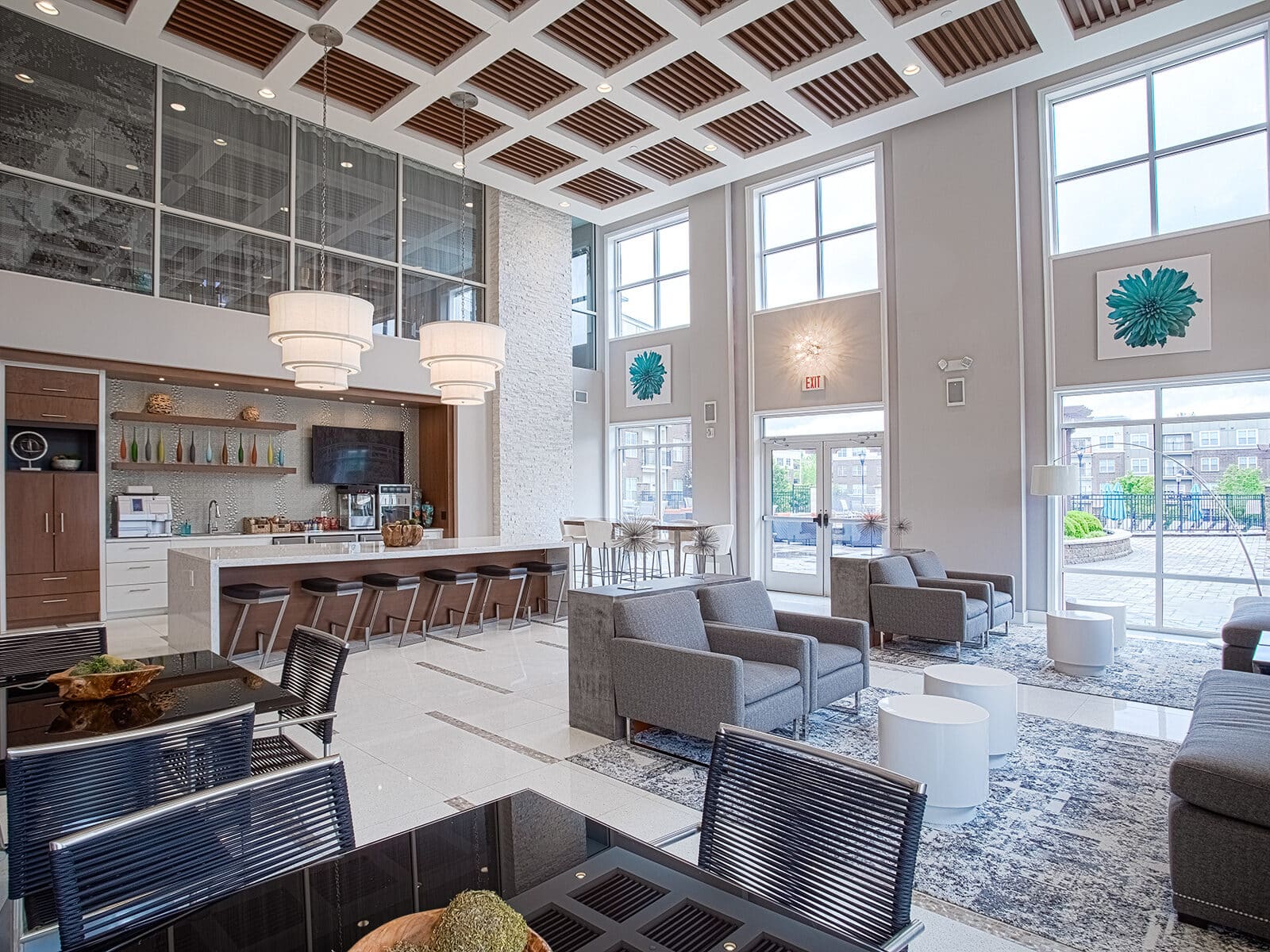 Spacious resident clubhouse and café area at Savoy at the Streets of West Chester in West Chester, Ohio, with high ceilings, modern seating, kitchen bar, and stylish community gathering spaces by HILLS Properties.